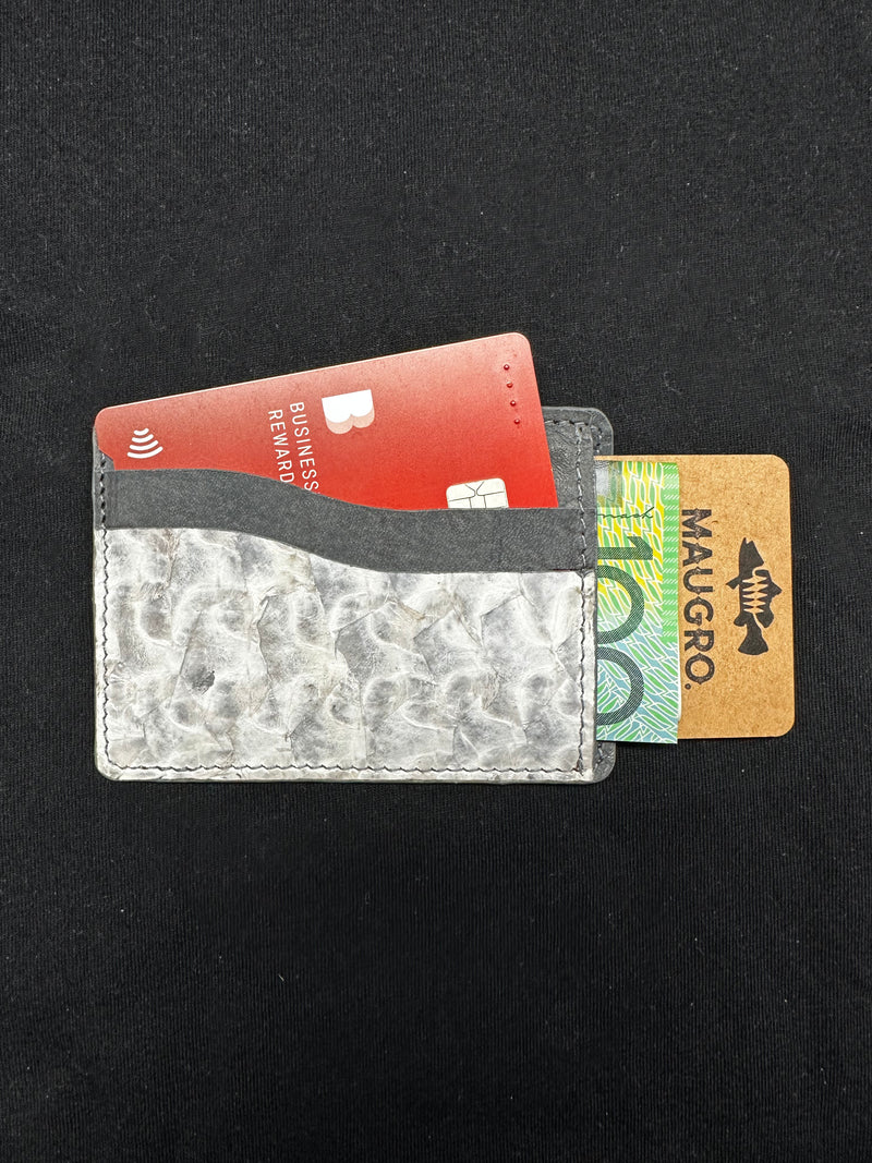 Slim barramundi leather card holder with a textured pattern, holding red, green, and brown cards.