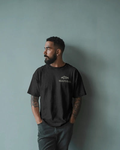 Black short-sleeve men's T-shirt with small light logo print on left chest, worn with hands in pockets.